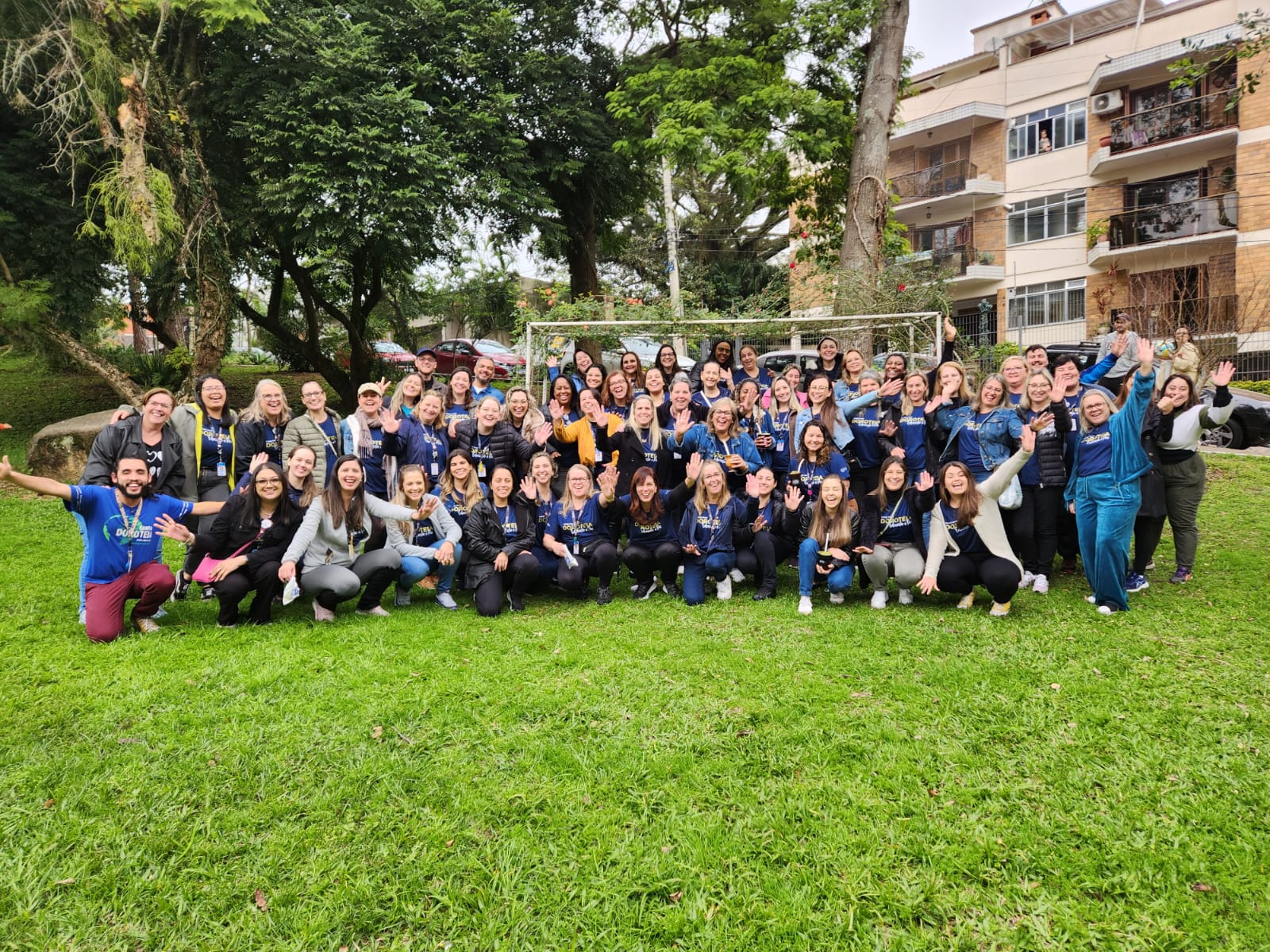 Funcionários do Colégio Santa Dorotéia Estão posando para a foto. Há homens e mulheres e estão em uma praça.